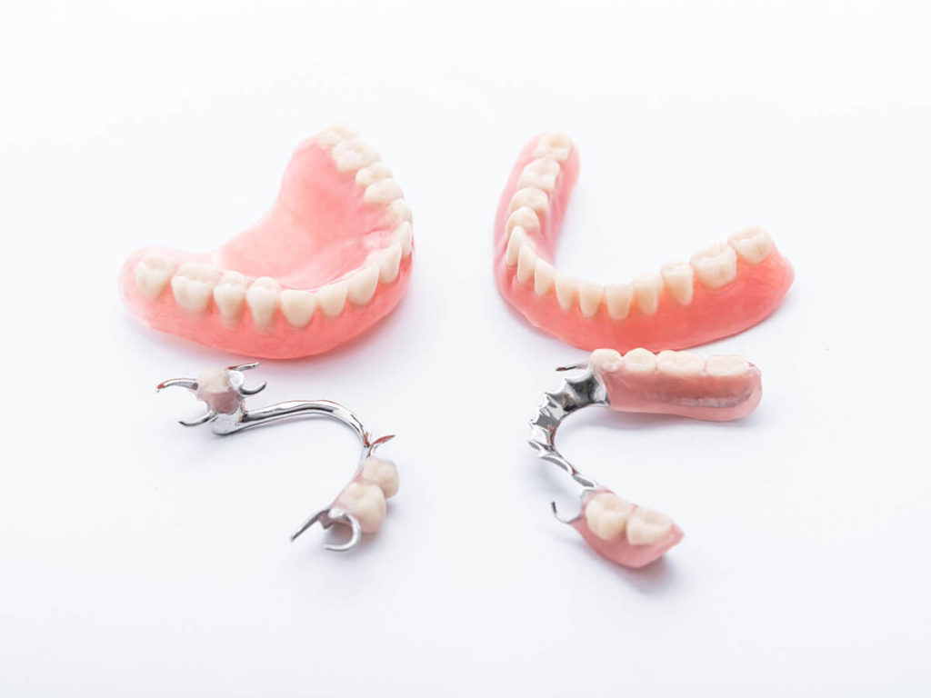 photo of full mouth dentures next to partial dentures