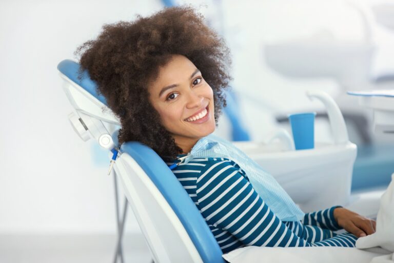 woman sitting in a dental chair smiling after getting a dental treatment
